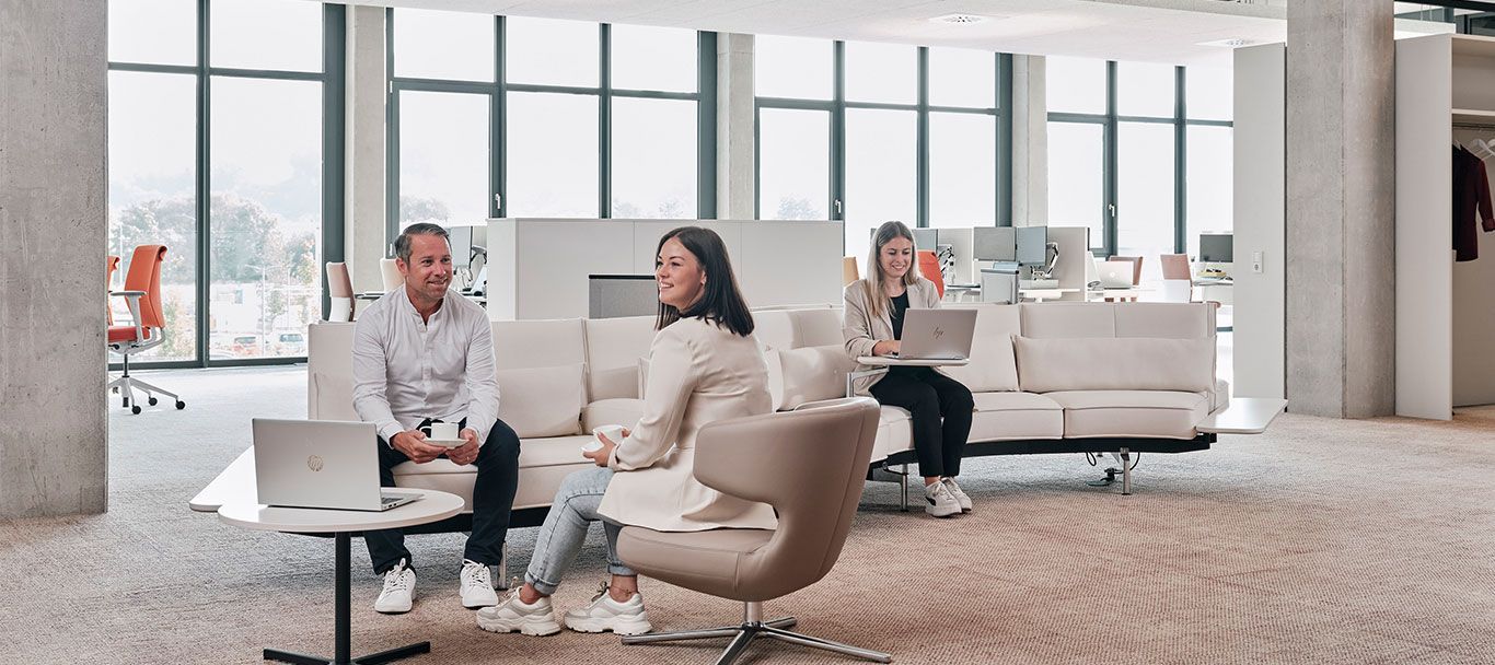 Mitarbeiter von Streit Service & Solution sitzen auf einem Sofa und arbeiten