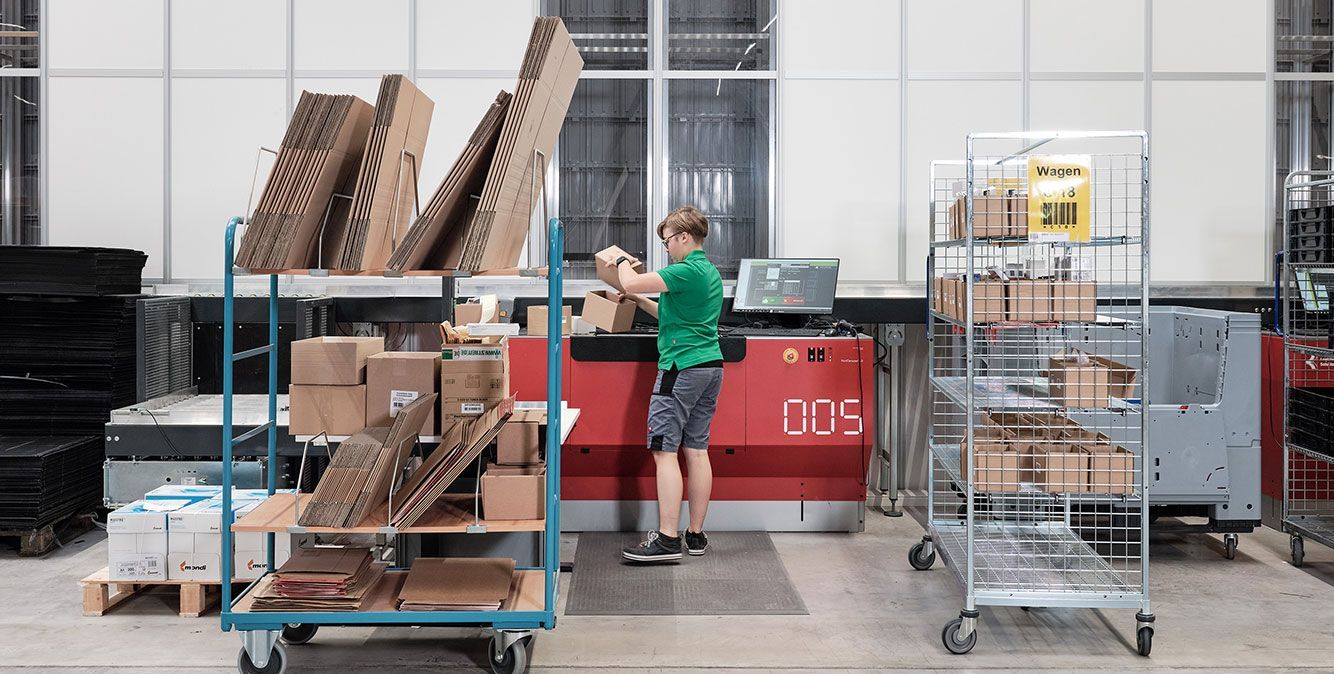 Mitarbeiterin von Streit Service & Solution packt ein Paket an der AutoStore Anlage im Logistikzentrum in Gengenbach