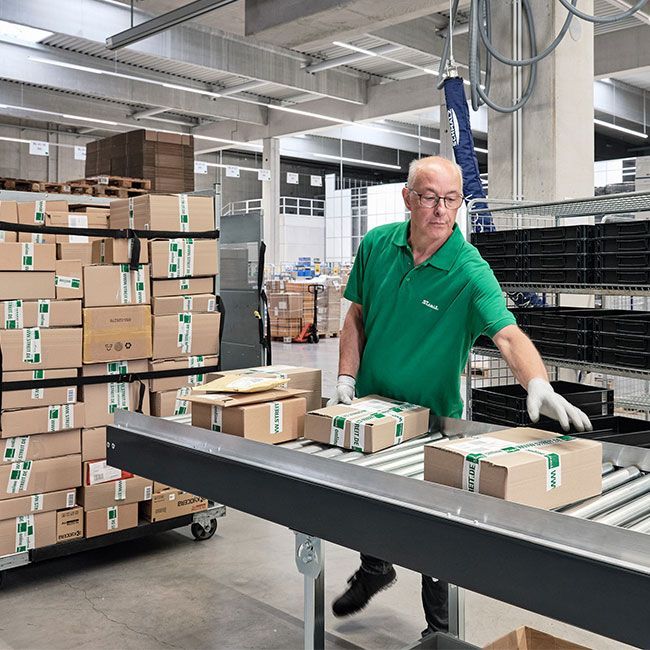 Mitarbeiter von Streit Service & Solution verladet Pakete im Logistikzentrum in Gengenbach