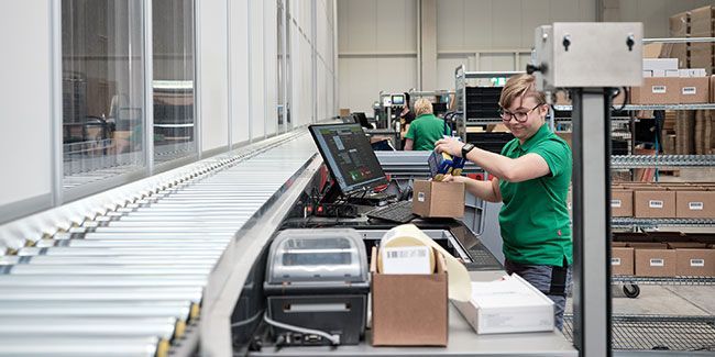 Mitarbeiterin von Streit Service & Solution packt ein Packet an der Pickstation der AutoStore Anlage im Logistikzentrum in Gengenbach