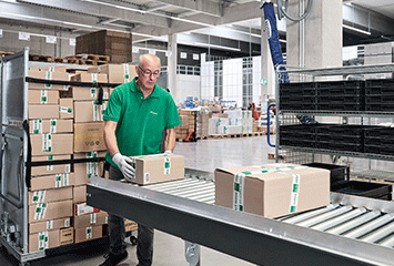 Mitarbeiter von Streit Service & Solution verladet Pakete im Logistikzentrum in Gengenbach