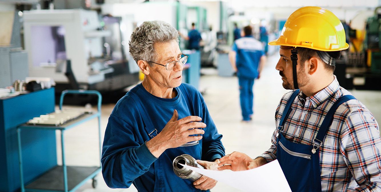 Arbeiter reden in der Produktionshalle miteinander