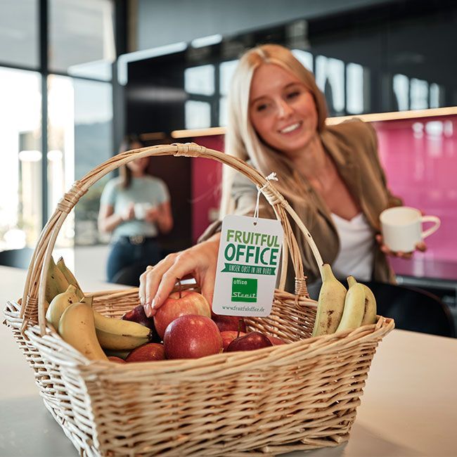 Mitarbeiterin von Streit Service & Solution nimmt sich einen Apfel aus dem Obstkrob