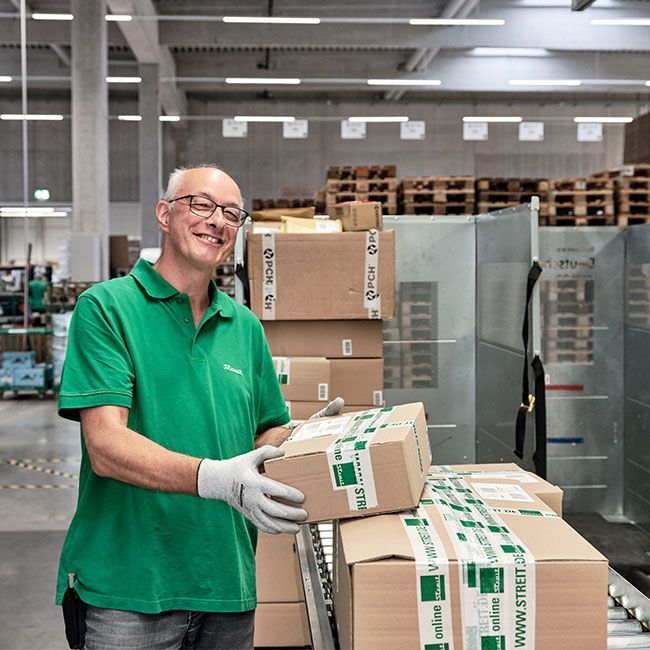Mitarbeiter von Streit Service & Solution verladet Pakete im Logistikzentrum in Gengenbach