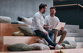 Mitarbeiter von Streit Service & Solution sitzen zusammen auf einer Treppe und schauen auf einen Laptop
