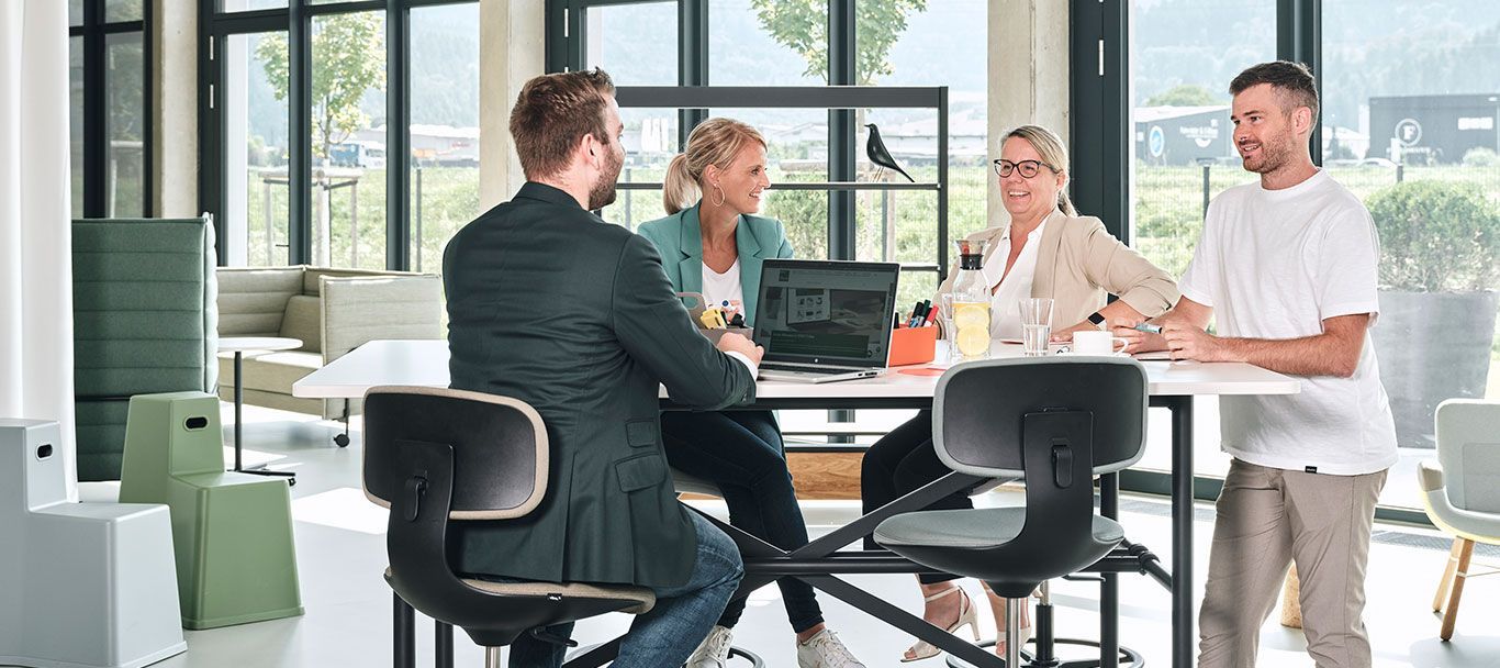 Vier Mitarbeiter des Unternehmens Streit Service & Solution sitzen zusammen an einem Tisch in der Arbeitswelt in Gengenbach und sprechen miteinander