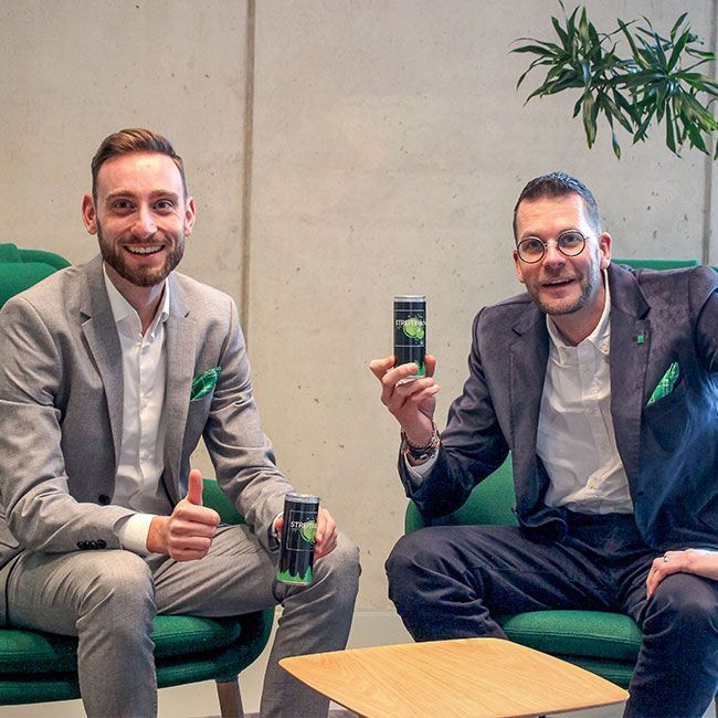 Zwei Mitarbeiter von Streit Service & Solution sitzen nebeneinander und halten Werbeartikel in der Hand