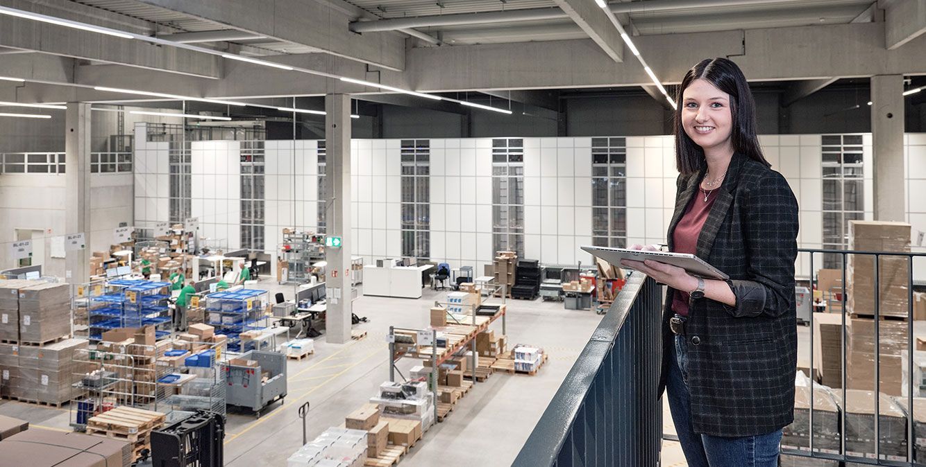 Mitarbeiterin von Streit Service & Solution steht im Logistikzentrum und arbeitet am Tablet