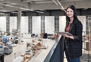 Mitarbeiterin von Streit Service & Solution steht im Logistikzentrum und arbeitet am Tablet
