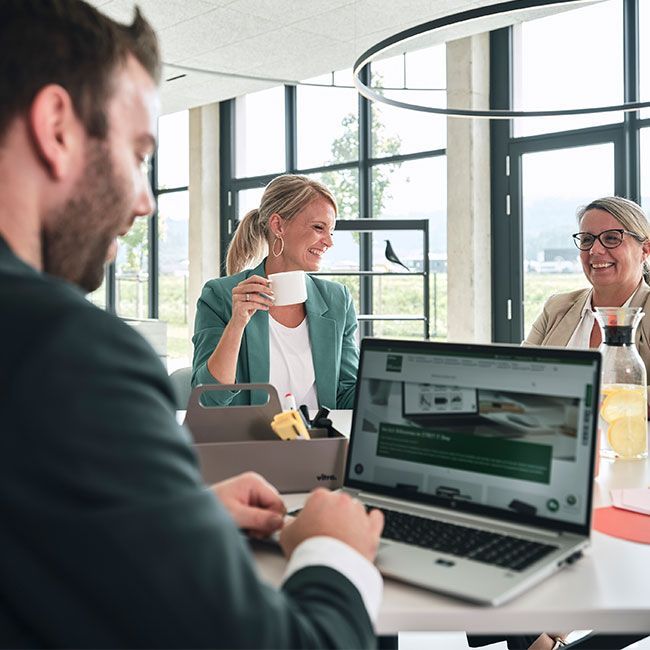 Mitarbeiter von Streit Service & Solution arbeiten zusammen und unterhalten sich. Ein Mitarbeiter arbeitet am Laptop.